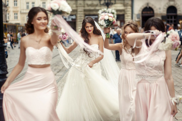 Adorable bride and beautiful bridesmaids in pink dresses walk al