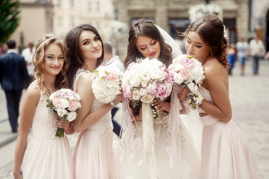 Beautiful bride and bridesmiads reach their bouquets to tender f