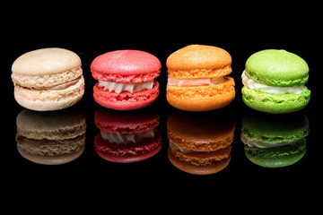 Multicolored macaroons isolated on black background with reflection