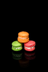 Multicolored macaroons isolated on black background with reflection. Free space for text