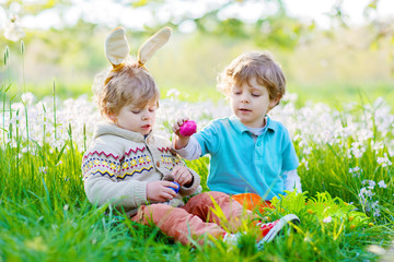 Two little boy friends in Easter bunny ears during egg hunt