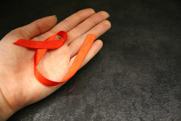 Red awareness ribbons in hand, isolated symbolic color logo concept lifting will campaign on health, public support for HIV STD cardiovascular disease