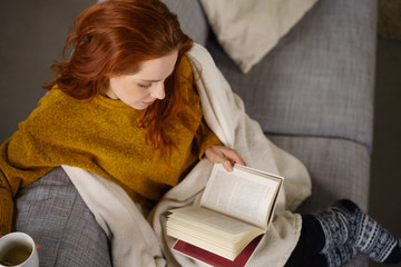 entspannte frau liest ein buch auf der couch