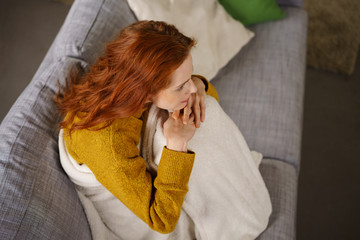 frau sitzt gemütlich mit einer decke auf dem sofa