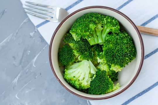Boiled broccoli in a bowl on a concrete background.