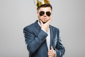 Thoughtful man in crown and sunglasses