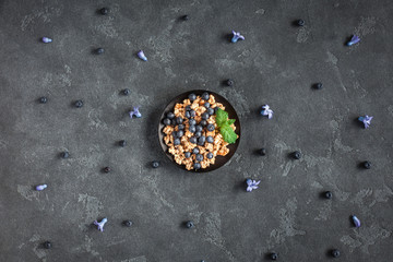Healthy breakfast with muesli and berries on black background. Flat lay, top view