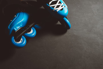 Close up view of blue roller skates inline skate or rollerblading on dark tinted grunge backgroung