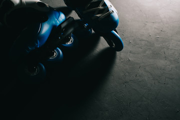Close up view of blue roller skates inline skate or rollerblading on dark tinted grunge backgroung