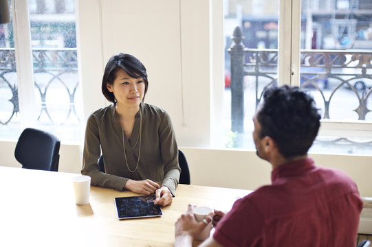 Asian businesswoman interviewing mixed race man in an office