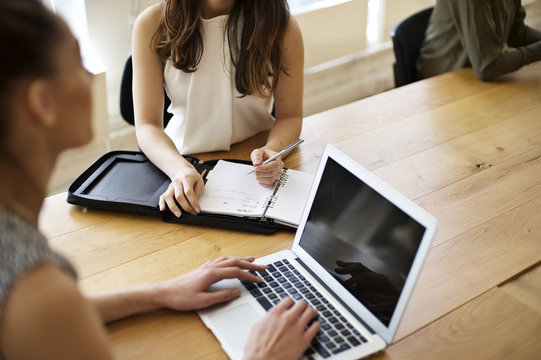 Caucasian and mixed race businesswomen hands typing and writing