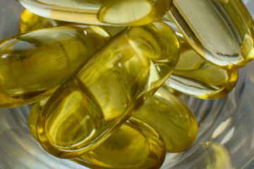 Fish oil capsules with omega 3 and vitamin D in a plastic bottle on a shiny texture, healthy diet concept