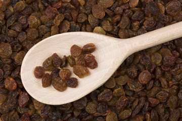 Raisins in a wooden spoon on raisins background