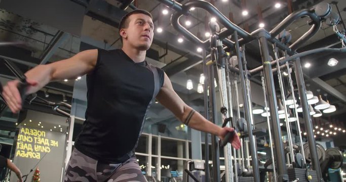 Man in gym doing pulls weight exercise 4k video. Male bodybuilder training chest muscles exercise using cable cross over machine for body mass. Workout and bodybuilding sport concept