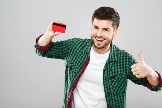 Man holding red credit card and showing thumbs up