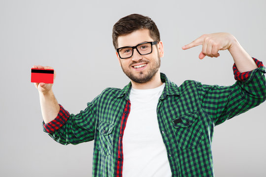 Man in eyeglasses pointing at red credit card