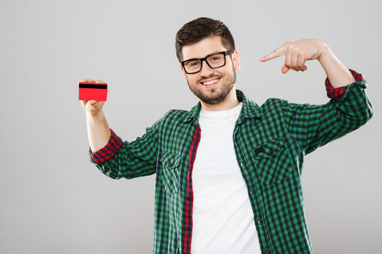 Young man in eyeglasses pointing at red credit card