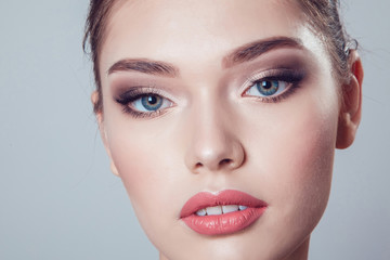 Beautiful brunette girl with makeup on grey background, youth and skin care concept.