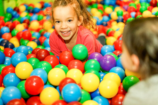 Cheerful children playing inside ball pit swimming pool