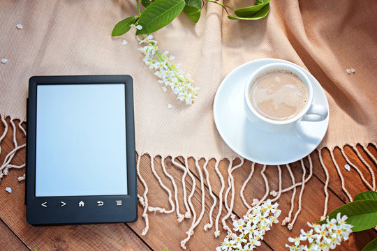 The e-book reader and coffee on a wooden table