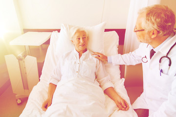 doctor visiting senior woman at hospital ward