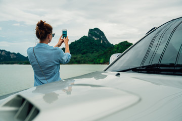 woman traveler taking pictures on the smartphone landscape mountain. Stop in the journey for taking photos, and share them on social networks.