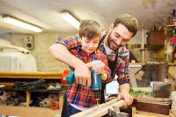 father and son with drill working at workshop