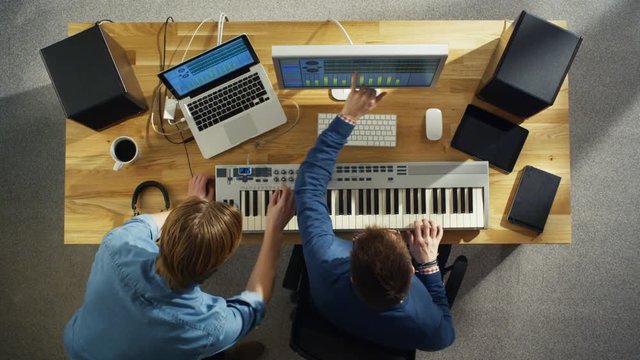 Top View of Two Audio Engineers Working in Their Sunny Studio. They Play on a Musical Keyboard and Experiment with Sound.  Shot on RED Cinema Camera in 4K (UHD).