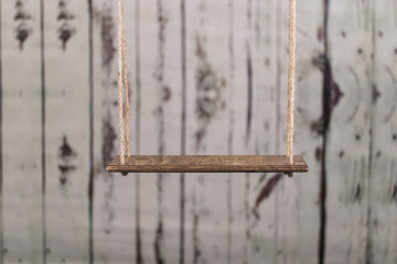 An old swing in front of a wooden background