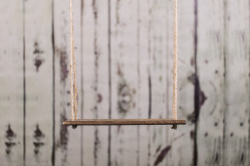 An old swing in front of a wooden background