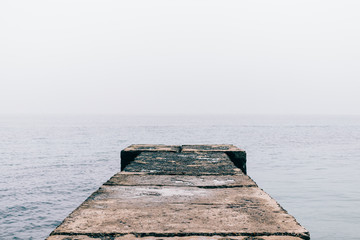 Old wet concrete pier on a cloudy day