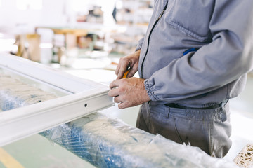 Factory for aluminum and PVC windows and doors production. Manual worker assembling PVC doors and windows. 