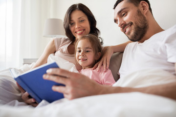 happy family reading book in bed at home