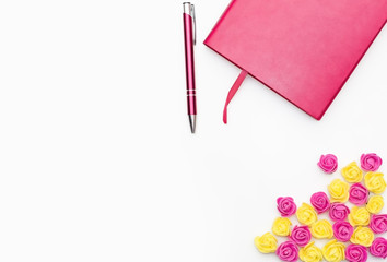 pink diary with a pen and small yellow pink roses on a white background, business minimal concept for women. Flat lay, top view.