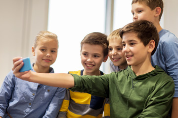 group of happy kids taking selfie with smartphone