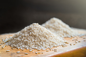 Two piles of white rice on wooden table background, metaphor ing