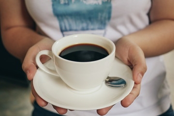 women hold a cup of Black coffee. Vintage tone. Selective Focus.