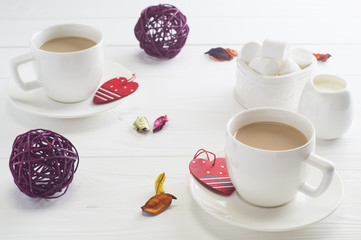 Romantic breakfast with couple white cups of coffee on white wooden background.  Valentine's day celebration concept with hearts and cups. Сocoa or coffee with milk with marshmallow.