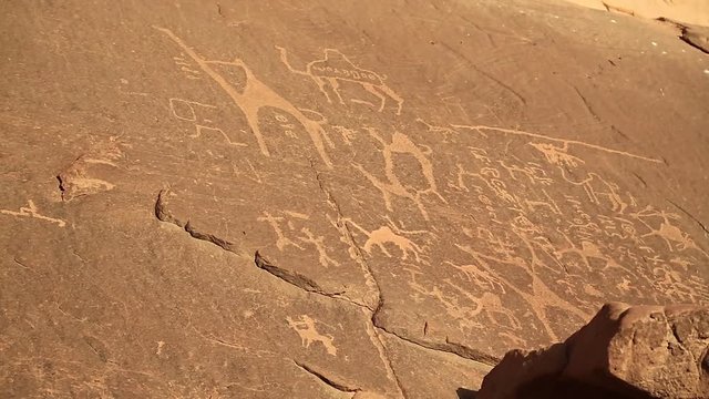 Ancient rock paintings, petroglyphs depicting humans and camels on the rock in Wadi Rum desert, Hashemite Kingdom of Jordan