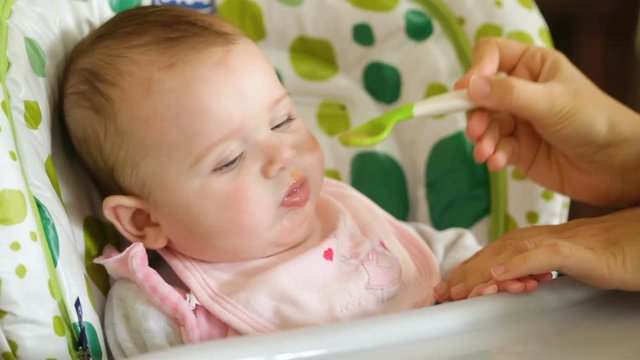 Baby eats first meals with fruit.