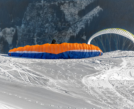 The pilot begins flight on a paraplane with a mountain-skiing slope of Penken on a sunny day - Mayrhofen, Austria