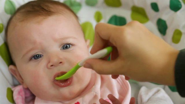 Baby eats first meals with fruit.
