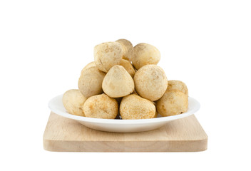 Close-up fresh straw mushrooms on white ceramic plate over wooden tray isolated on white background