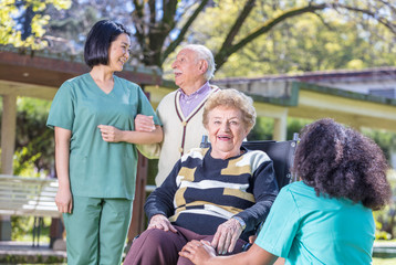 Happy nurses and patients in rehab clinic garden