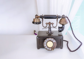 Ancient phone is placed on a wooden table, vintage style.