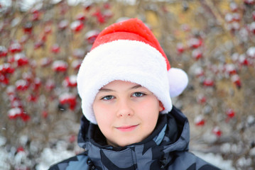 Teen in cap Santa Claus on background of Viburnum