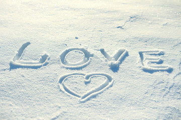 The word love and a heart drawn in the snow.