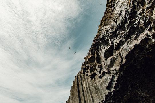 Birds flying by rock formation 