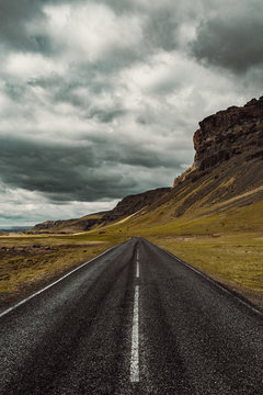 View of empty road by mountain against cloudy sky