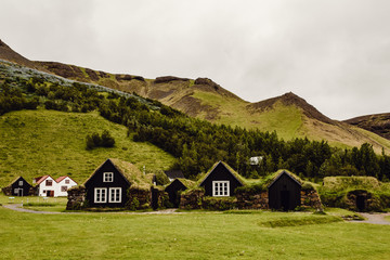 Grass roofed cottages by hills 